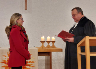 links Andrea Betz, blond mit roter Jacke, ihr gegenüber steht Dekan Jörg Breu im Talar.